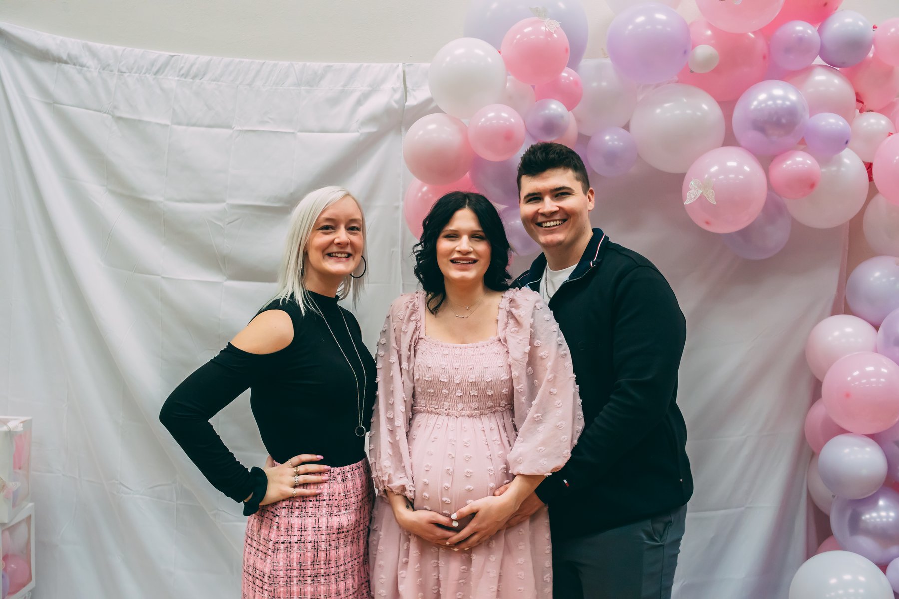 Guests celebrating together in front of a pink and white balloon arch