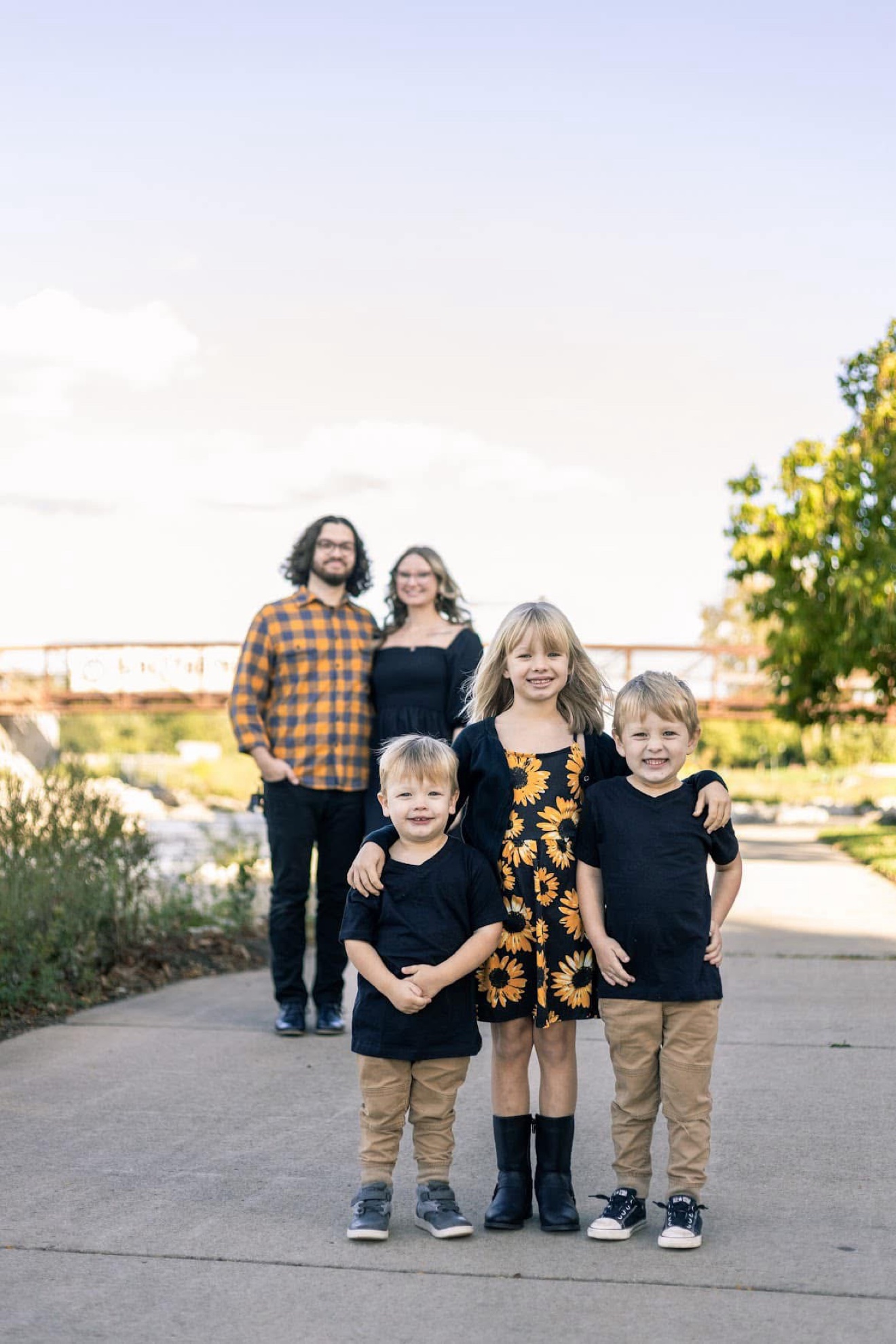 A family of five on a riverside path, the three kids in front and their parents behind
