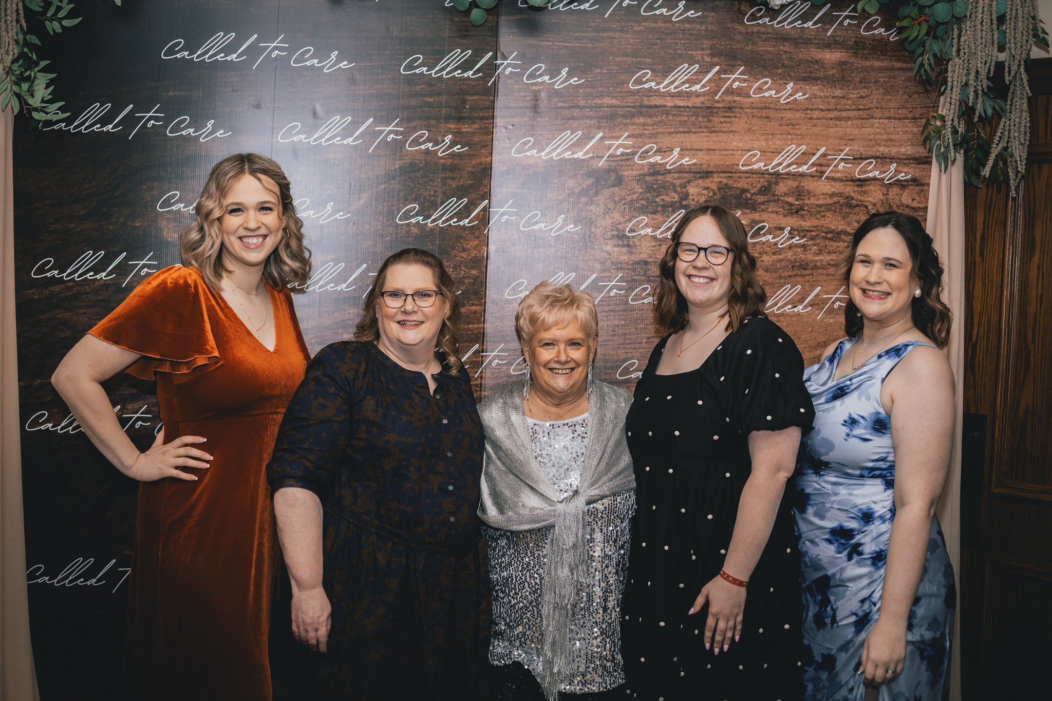 Five women posing together at a Called to Care event backdrop