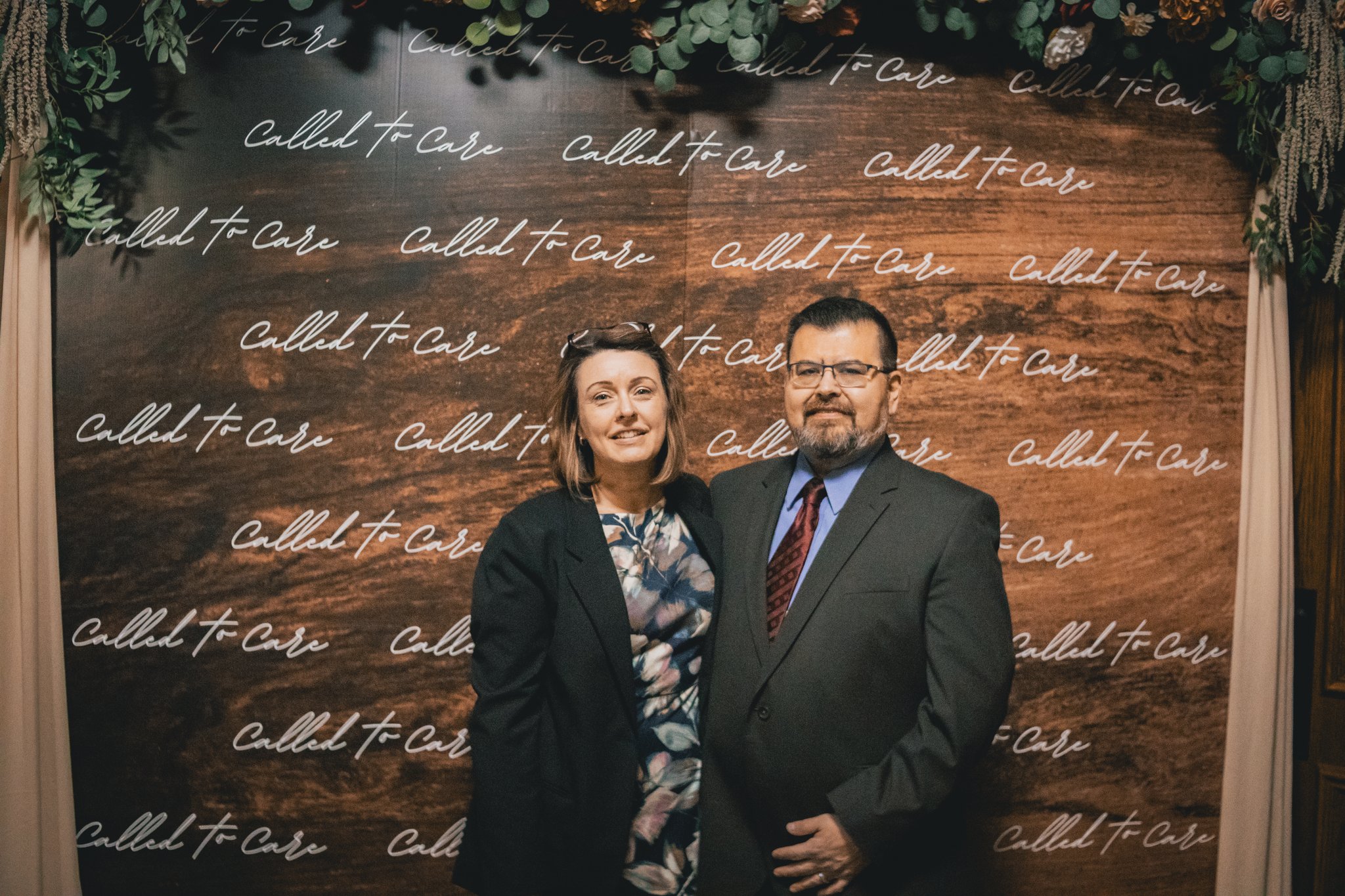 A couple posing together at a Called to Care event backdrop
