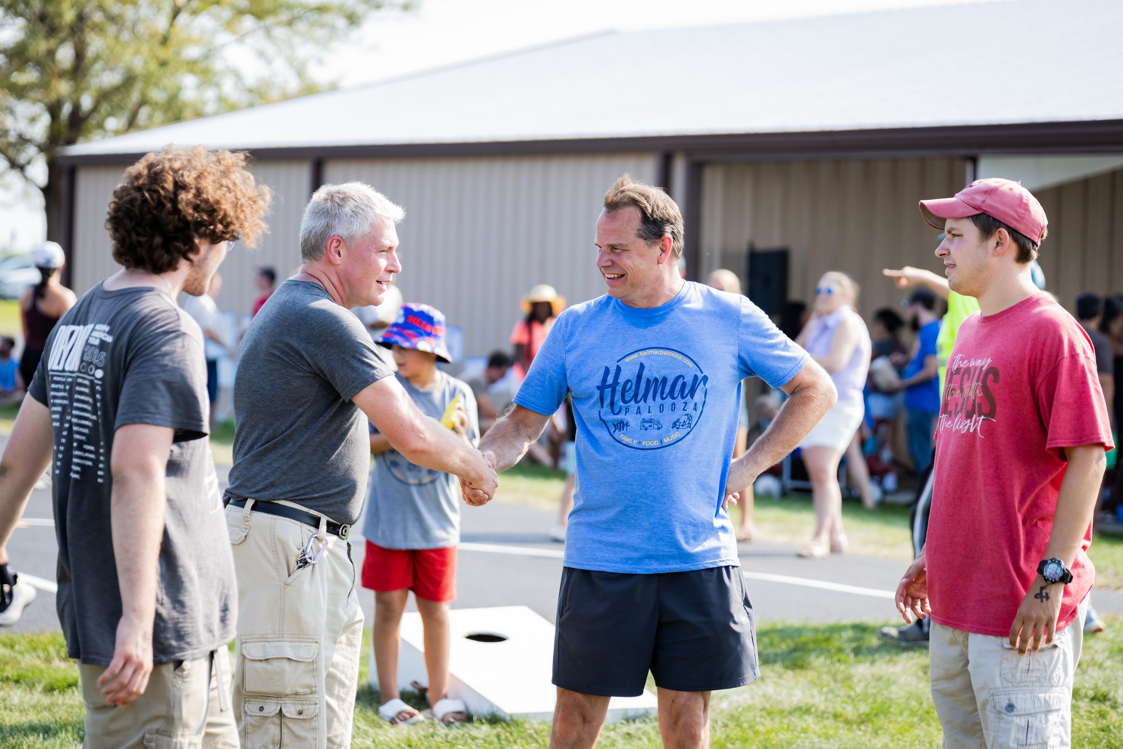 Helmarpalooza 2025, two men shaking hands with a group gathered around them