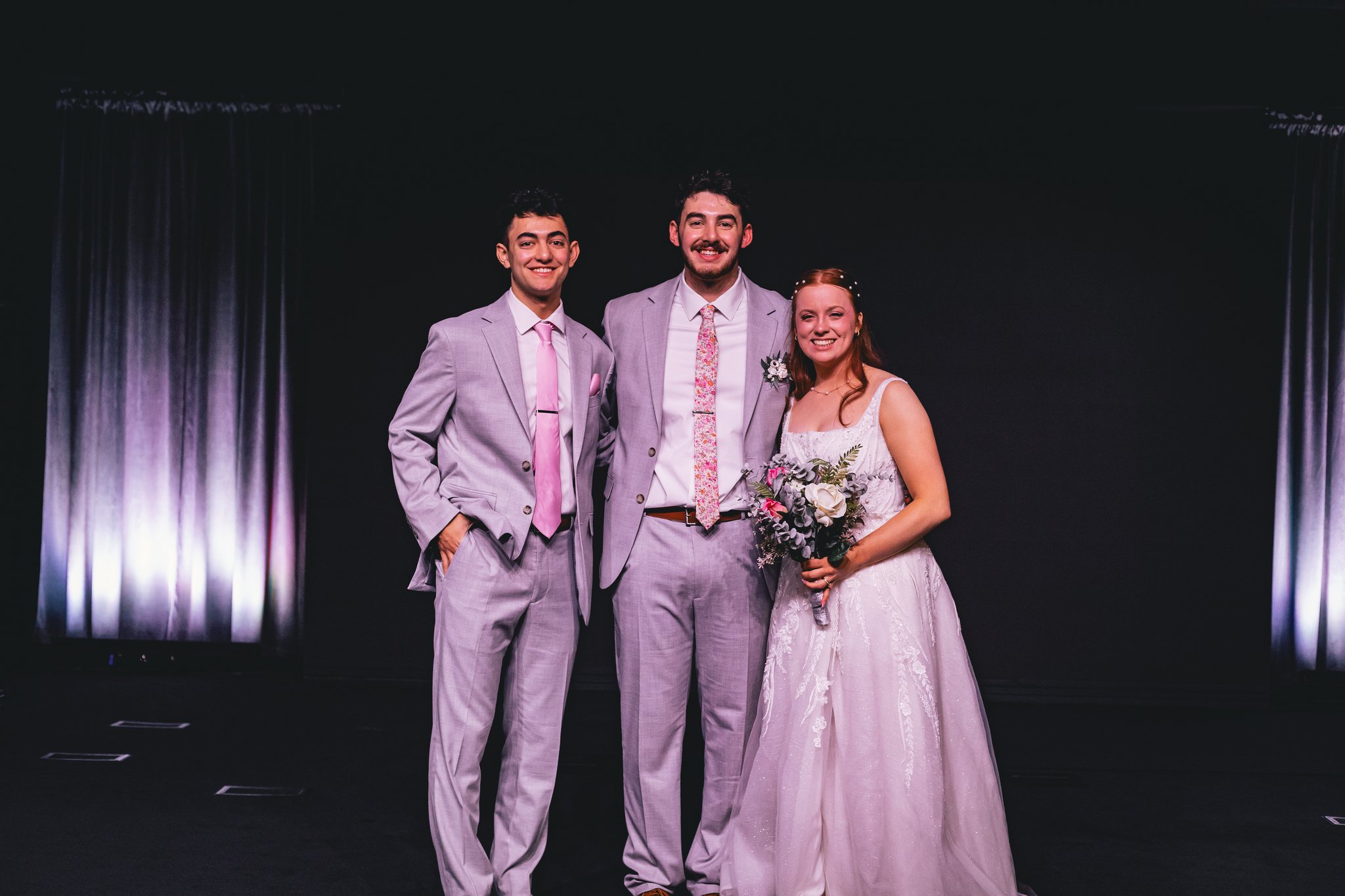 A groom, groomsman, and bride posing together