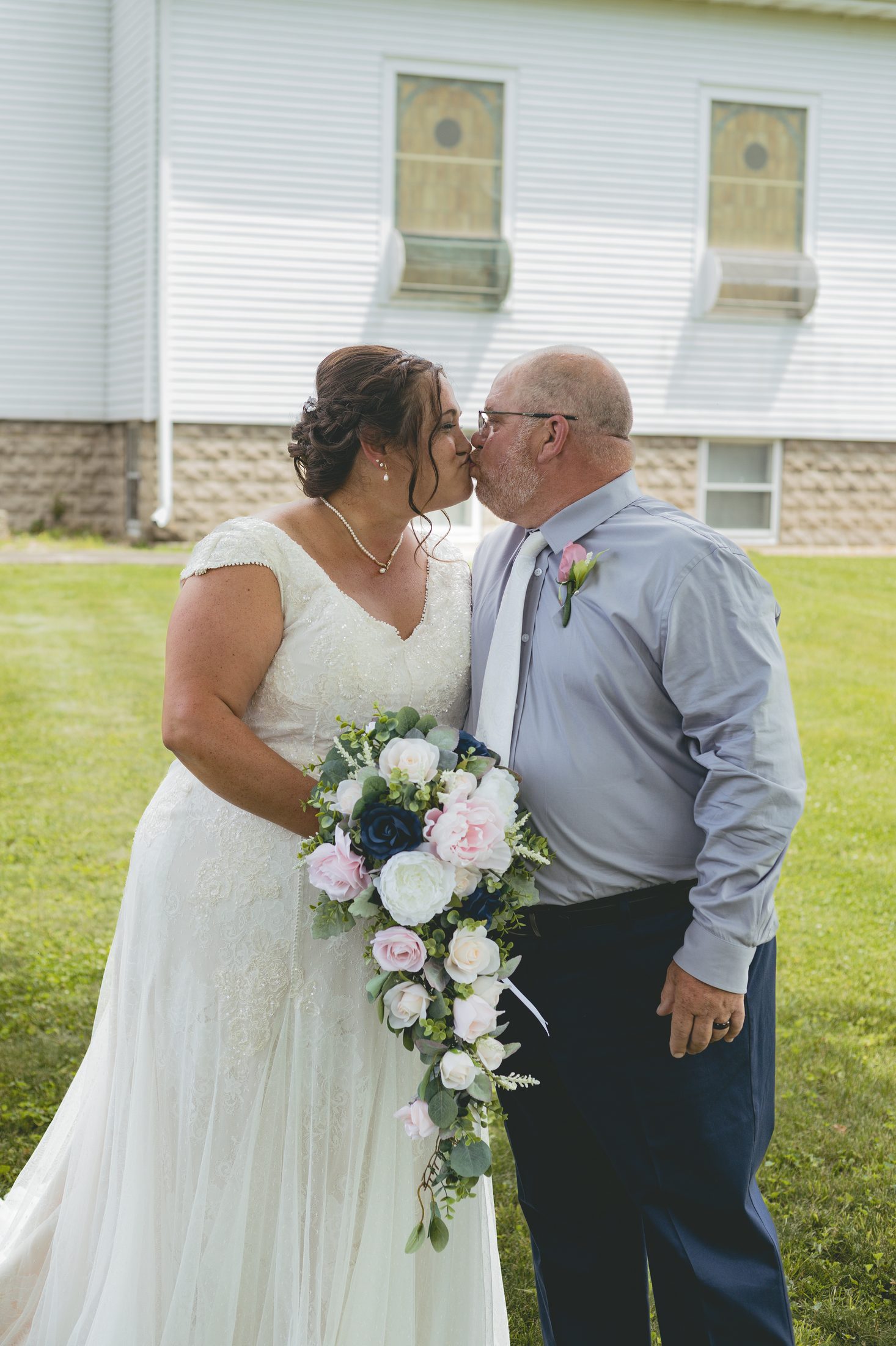 The Davidson bride and groom kissing, the bride holding her bouquet